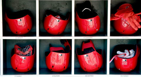 Cincinnati Reds helmets are stacked in the dugout.