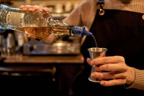 A bartender pours whiskey.