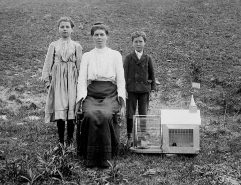 A mother and her children pose with their pet squirrel.