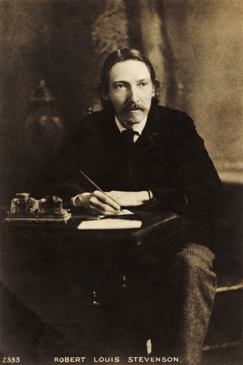 Robert Louis Stevenson, writing at his desk.