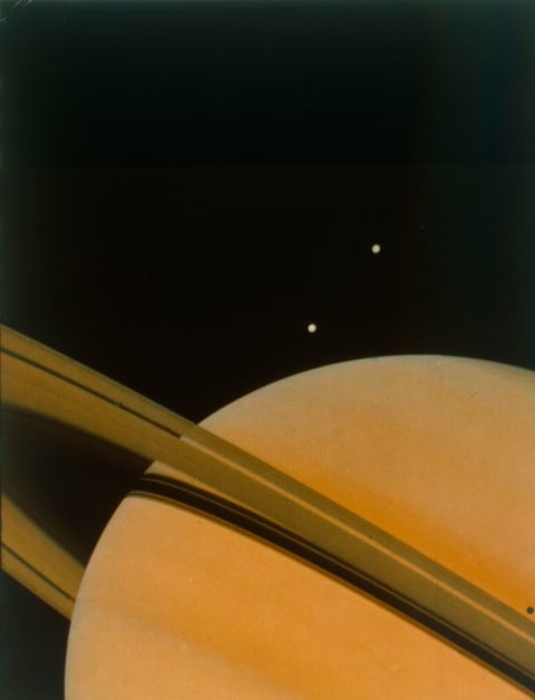 The planet Saturn with moons Tethys and Dione.