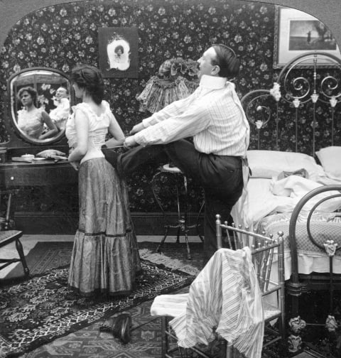 A man helping his wife with her corset.