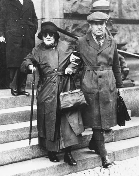 Clara Zetkin being helped down the steps of a church in 1932.