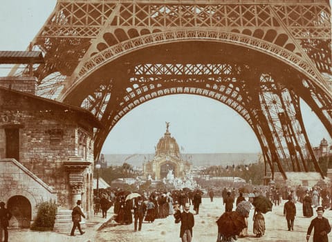 Pedestrians walk under Eiffel Tower at the 1889 World's Fair.