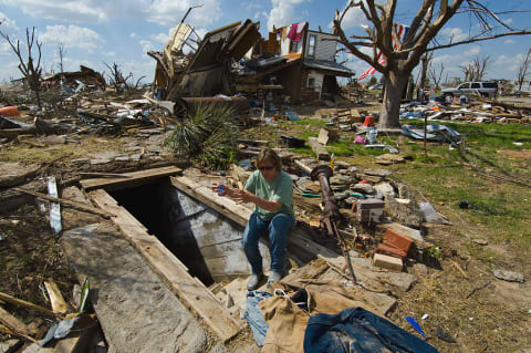 A woman sits at the entrance of her storm shelter amid debris from a powerful tornado in Kansas.