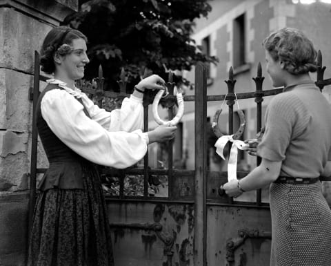 Two women tying horseshoes to a gate, circa 1937.