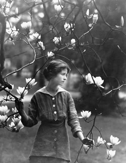 Poet Edna St. Vincent Millay posing with a magnolia.