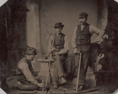 Three Plumbers With Pipes And Tools.