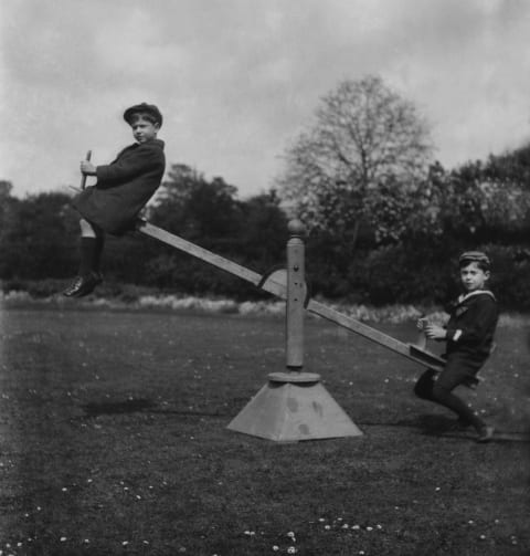 Boys playing on seesaw, circa 1900.