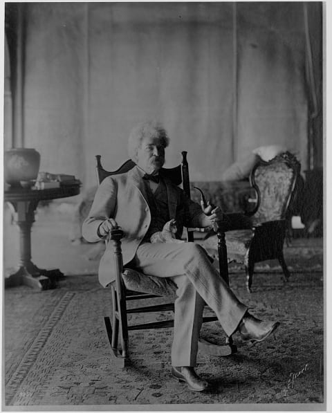 Mark Twain with a kitten in his lap.