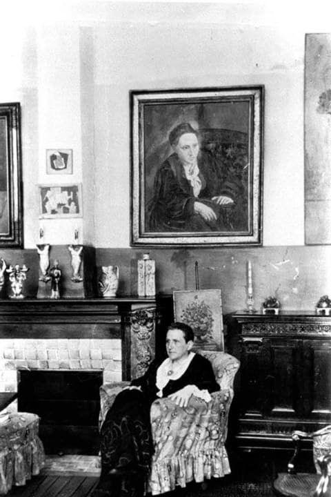 Gertrude Stein at home with her portrait by Picasso, circa 1935.