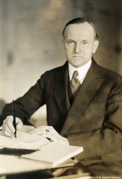 Calvin Coolidge seated at his desk.