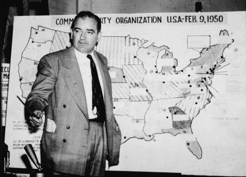 Joseph McCarthy stands in front of a map purporting to show communist activity across the U.S.