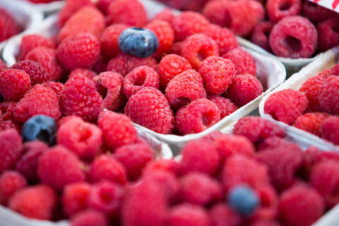 An assortment of raspberries, featuring a few bonus blueberries.