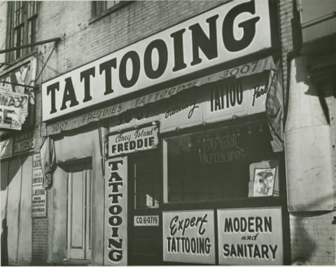 IRVING HERZBERG, TATTOO SHOP OF “CONEY ISLAND FREDDIE” JUST PRIOR TO NEW YORK CITY’S BAN ON TATTOOING, 1961, DIGITAL PRINT, BROOKLYN PUBLIC LIBRARY