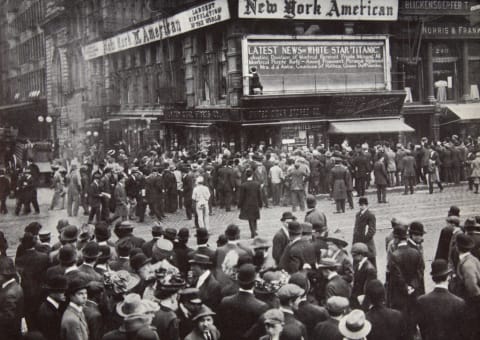 People gather around newspaper bulletin boards as reports of the 'Titanic' sinking arrive in New York.