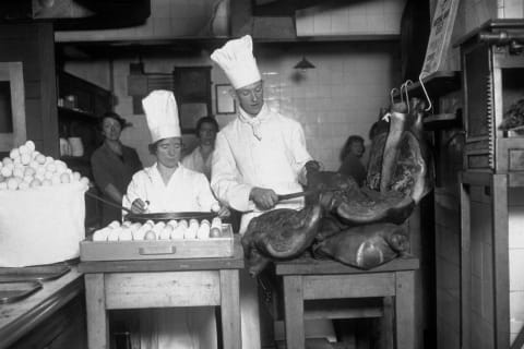 Chefs preparing ham and eggs for breakfast circa 1930.