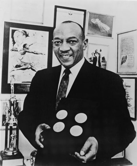 Jesse Owens, in the late 1950s, poses with the four gold medals he won at the 1936 Berlin Olympics.