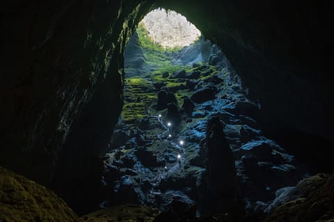 Hikers' headlamps shine as they walk up a steep path toward a doline in Son Doong cave.