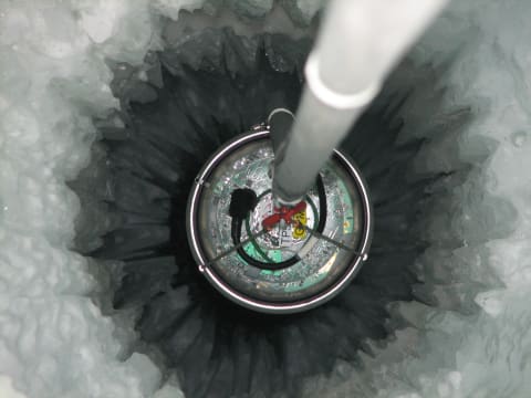 A sensor called a Digital Optical Module is lowered one mile into Antarctica's ice under the IceCube neutrino detector.