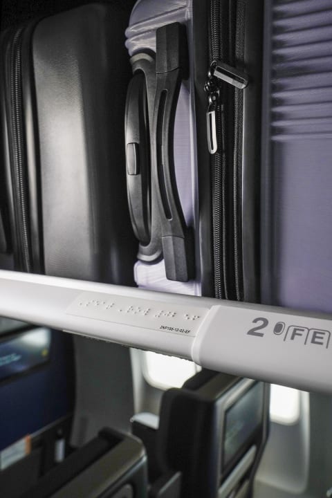 Braille signage underneath an overhead compartment.