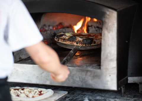 A wood-fired pizza oven at work.