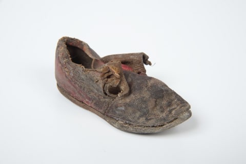 A child's single leather latchet tie shoe (1740-1760), originally red, was found under floorboards in a manor house in Gloucestershire, UK.