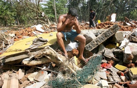 A man sits atop wreckage left behind after the 2004 Indian Ocean tsunami struck Sri Lanka.