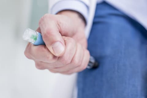 A woman injects herself with an EpiPen.