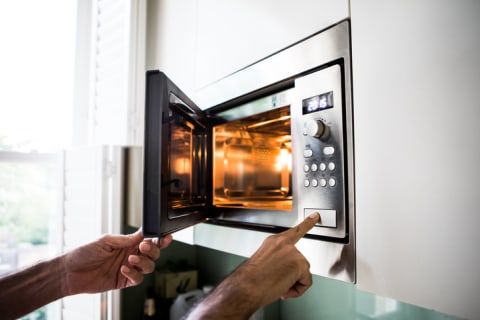 A man using a microwave oven.