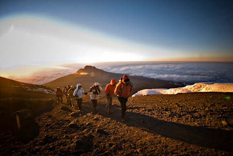 A group of hiker approach Kili’s summit at sunrise.