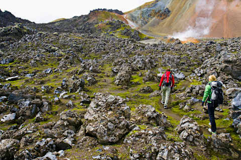 Hikers cross a boulder field near a geothermal feature on Iceland’s Laugavegur Trail.