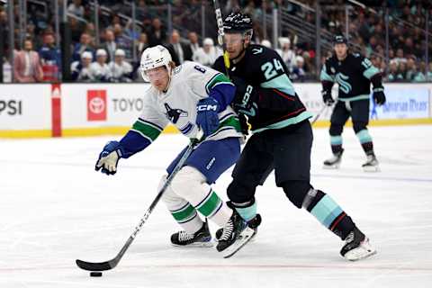 Brock Boeser shields the puck from Kraken defenseman Jamie Oleksiak. (Photo by Steph Chambers/Getty Images)