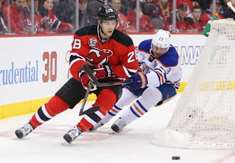 Feb 9, 2016; Newark, NJ, USA; New Jersey Devils defenseman Damon Severson (28) skates with the puck while being defended by Edmonton Oilers center Matt Hendricks (23) during the first period at Prudential Center. Mandatory Credit: Ed Mulholland-USA TODAY Sports