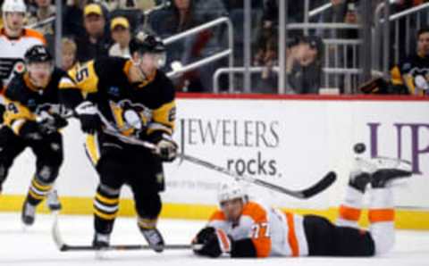 Apr 2, 2023; Pittsburgh, Pennsylvania, USA; Pittsburgh Penguins center Ryan Poehling (25) chips the puck past Philadelphia Flyers defenseman Tony DeAngelo (77) on his way to scoring an empty net goal during the third period at PPG Paints Arena. The Penguins won 4-2. Mandatory Credit: Charles LeClaire-USA TODAY Sports