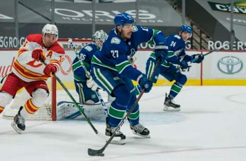 May 18, 2021; Vancouver, British Columbia, CAN; Calgary Flames forward Mikael Backlund (11) checks Vancouver Canucks defenseman Travis Hamonic (27) in the second period at Rogers Arena. Mandatory Credit: Bob Frid-USA TODAY Sports