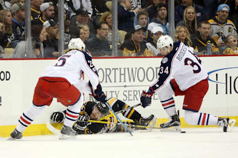 Feb 3, 2017; Pittsburgh, PA, USA; Pittsburgh Penguins left wing Scott Wilson (23) passes the puck while on his back as Columbus Blue Jackets center William Karlsson (25) and right wing Josh Anderson (34) defend during the first period at the PPG PAINTS Arena. Mandatory Credit: Charles LeClaire-USA TODAY Sports