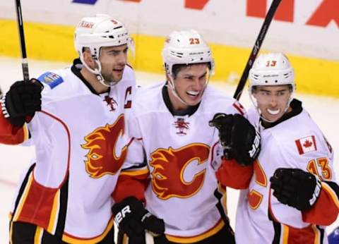 Oct 10, 2015; Vancouver, British Columbia, CAN; Calgary Flames forward Sean Monahan (23) celebrates his goal with defenseman Mark Giordano (5) and forward Johnny Gaudreau (13) against Vancouver Canucks goaltender Ryan Miller (30) (not pictured) during the third period at Rogers Arena. The Calgary Flames won 3-2. Mandatory Credit: Anne-Marie Sorvin-USA TODAY Sports