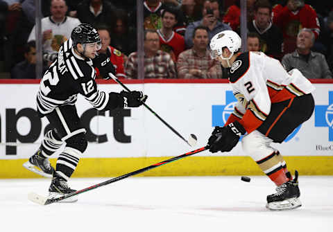 Alex DeBrincat #12 of the Chicago Blackhawks shoots past Brendan Guhle #2 of the Anaheim Ducks (Photo by Jonathan Daniel/Getty Images)