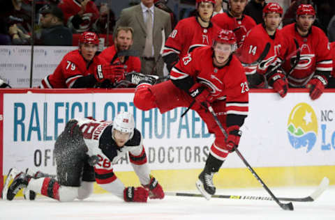 RALEIGH, NC – APRIL 4: Brock McGinn #23 of the Carolina Hurricanes fires the puck at the empty net after jumping over Damon Severson #28 of the New Jersey Devils during an NHL game at PNC Arena on April 4, 2019, in Raleigh, North Carolina. (Photo by Gregg Forwerck/NHLI via Getty Images)