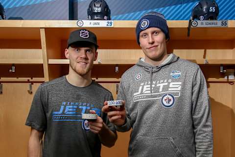 WINNIPEG, MB – NOVEMBER 29: Nikolaj Ehlers #27 and Patrik Laine #29 of the Winnipeg Jets pose with their game pucks following a 6-5 victory over the Chicago Blackhawks at the Bell MTS Place on November 29, 2018 in Winnipeg, Manitoba, Canada. Ehlers recorded his third career hat trick while Laine scored his 100th career NHL goal. (Photo by Jonathan Kozub/NHLI via Getty Images)