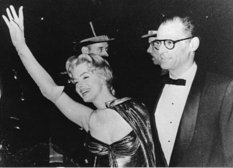 Marylin Monroe waves to the camera with husband Arthur Miller on her arm in 1958.