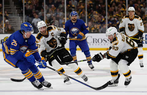 Dec 31, 2022; Boston, Massachusetts, USA; Boston Bruins left wing Brad Marchand (63), center Patrice Bergeron (37) and Buffalo Sabres defenseman Owen Power (25) battle for a loose puck during the third period at TD Garden. Mandatory Credit: Winslow Townson-USA TODAY Sports