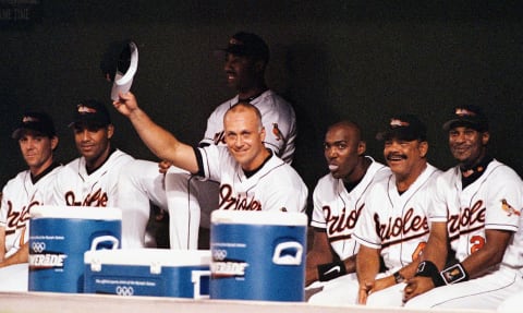 BALTIMORE, : In this 20 September 1998 file photo, Baltimore Orioles third baseman Cal Ripken Jr. (C) tips his hat to the New York Yankees players who joined fans at Camden Yards in Baltimore, MD for a standing ovation to acknowledge Ripken’s consecutive game streak which ended 20 September. Ripken said before the game that he planned to end his consecutive game streak in the Orioles’ final home game of the season. The Orioles announced late 19 April 1999 that Ripken has been placed on the 15-day disabled list because he is suffering from nerve irritation in his back. It is the first time in his 19-year career that he has been placed on the list. AFP PHTO/FILES/Heather HALL (Photo credit should read HEATHER HALL/AFP/Getty Images)