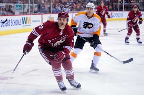 Jan 4, 2014; Glendale, AZ, USA; Phoenix Coyotes left wing Paul Bissonnette (12) and Philadelphia Flyers center Chris Vande Velde (76) watch the puck during the first period at Jobing.com Arena. Mandatory Credit: Matt Kartozian-USA TODAY Sports