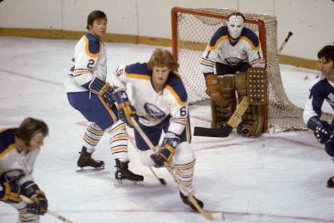 Canadian professional hockey player Tim Horton (1930 – 1974) (center) of the Buffalo Sabres skates in front of goalie Roger Crozier (standing in goal) as teammate Jim Schoenfeld (left) defends during a game against the Toronto Maple Leafs at the Buffalo Memorial Auditorium, Buffalo, New York, early 1970s. (Photo by Melchior DiGiacomo/Getty Images)