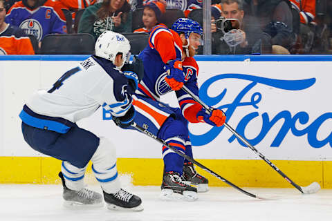 Oct 21, 2023; Edmonton, Alberta, CAN; Edmonton Oilers forward Connor McDavid (97) tries to protect the puck from Winnipeg Jets defensemen Neal Pionk (4) during the third period at Rogers Place. Mandatory Credit: Perry Nelson-USA TODAY Sports