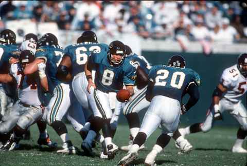 JACKSONVILLE, FL – DECEMBER 22: Mark Brunell #8 of the Jacksonville Jaguars turns to handoff to Natrone Means #20 against the Atlanta Falcons during an NFL football game December 22, 1996 at Jacksonville Municipal Stadium in Jacksonville, Florida. Brunell played for the Jaguars from 1995-2003. (Photo by Focus on Sport/Getty Images)