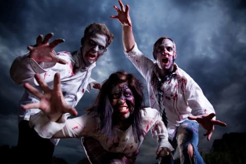 Three zombies reaching for the viewer against a stormy sky