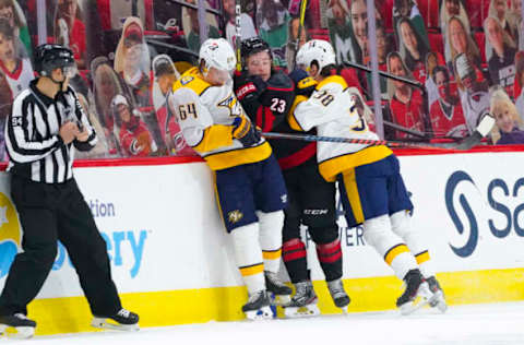 Mar 9, 2021; Raleigh, North Carolina, USA; Nashville Predators defensemen Jeremy Davies (38) and center Mikael Granlund (64) check Carolina Hurricanes left wing Brock McGinn (23) during the third period at PNC Arena. Mandatory Credit: James Guillory-USA TODAY Sports